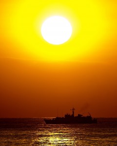 The Royal Navy's Sandown Class Minehunter HMS Pembroke is pictured with the sun setting behind her as she enters Dubai during operations in the Middle East.