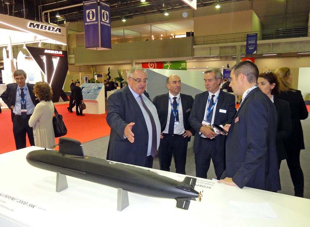 Hervé Guillou, CEO of DCNS (at left), in conversation with members of his personnel in front of a 1/50 scale model of the 5,000-ton Scorpene 2000 ; the latest export variant of this very successful SSK. © J.-M. Guhl